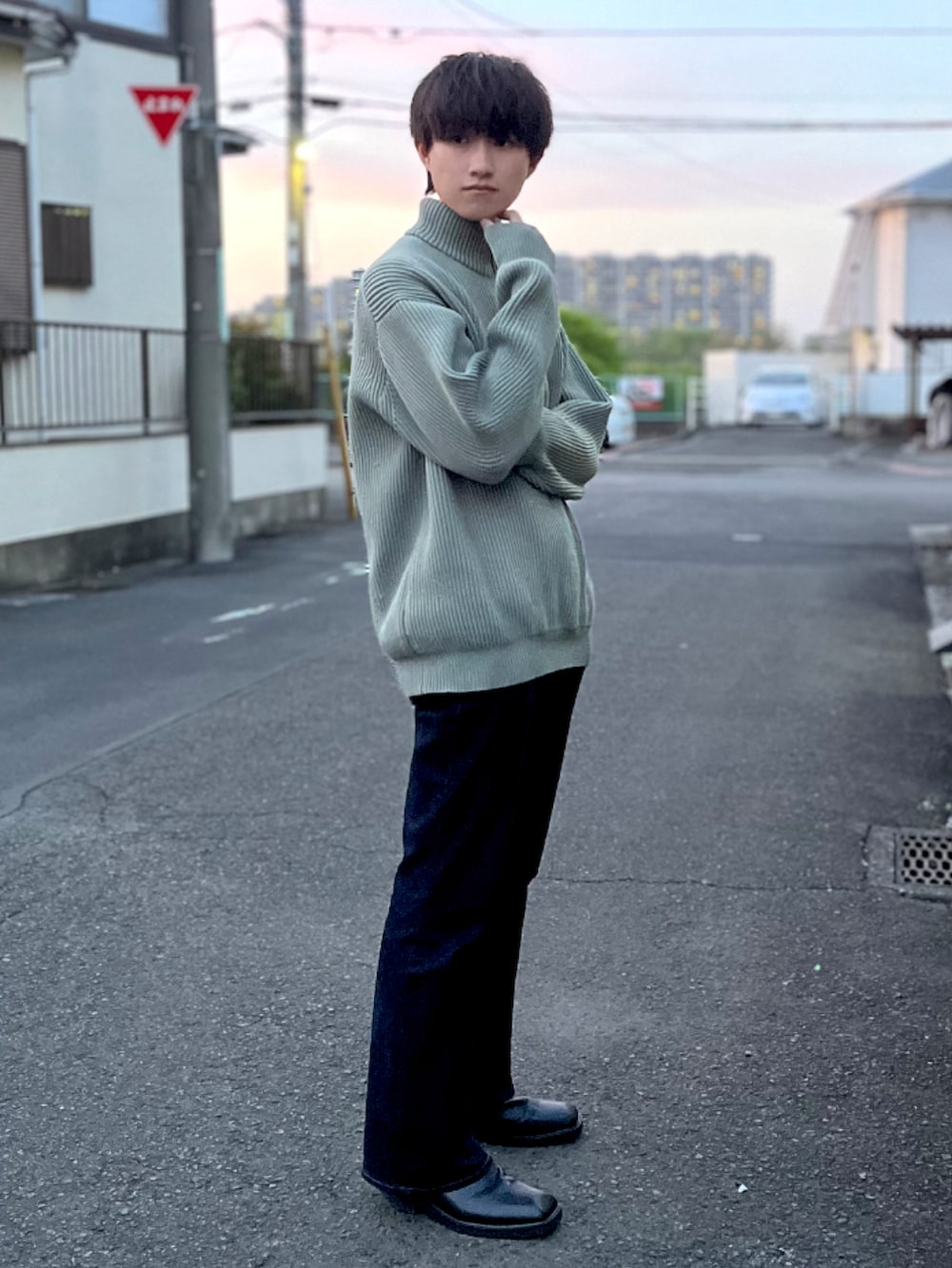 ブルー系のデニムパンツ、ブラック系のブーツ、グリーン系のニット/セーターを着用したメンズの春コーディネートの2枚目の写真