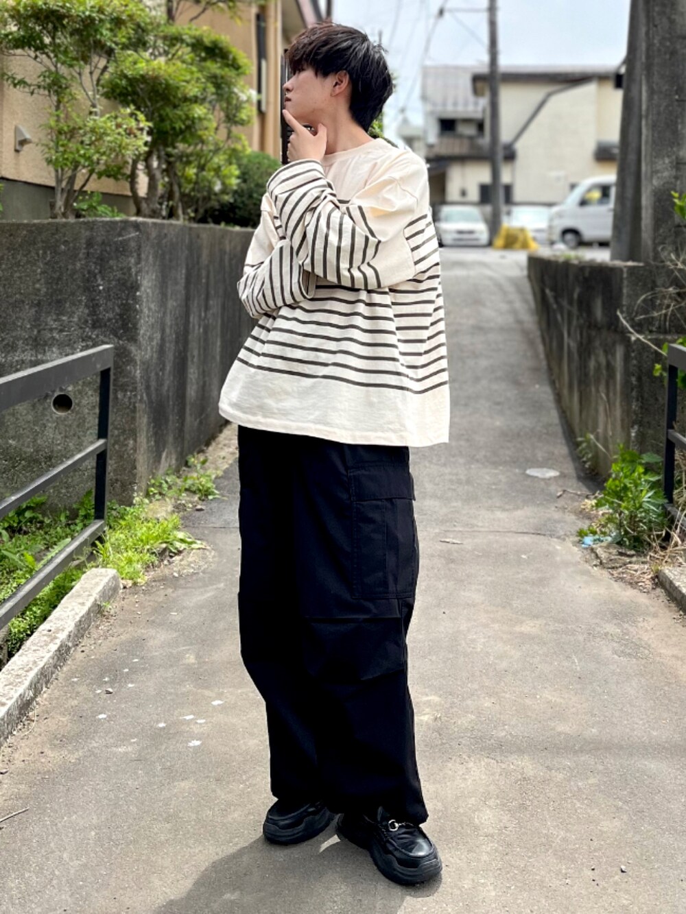 ブラック系のカーゴパンツ、ブラック系のスニーカー、グリーン系のTシャツ/カットソーを着用したメンズの春コーディネートの2枚目の写真