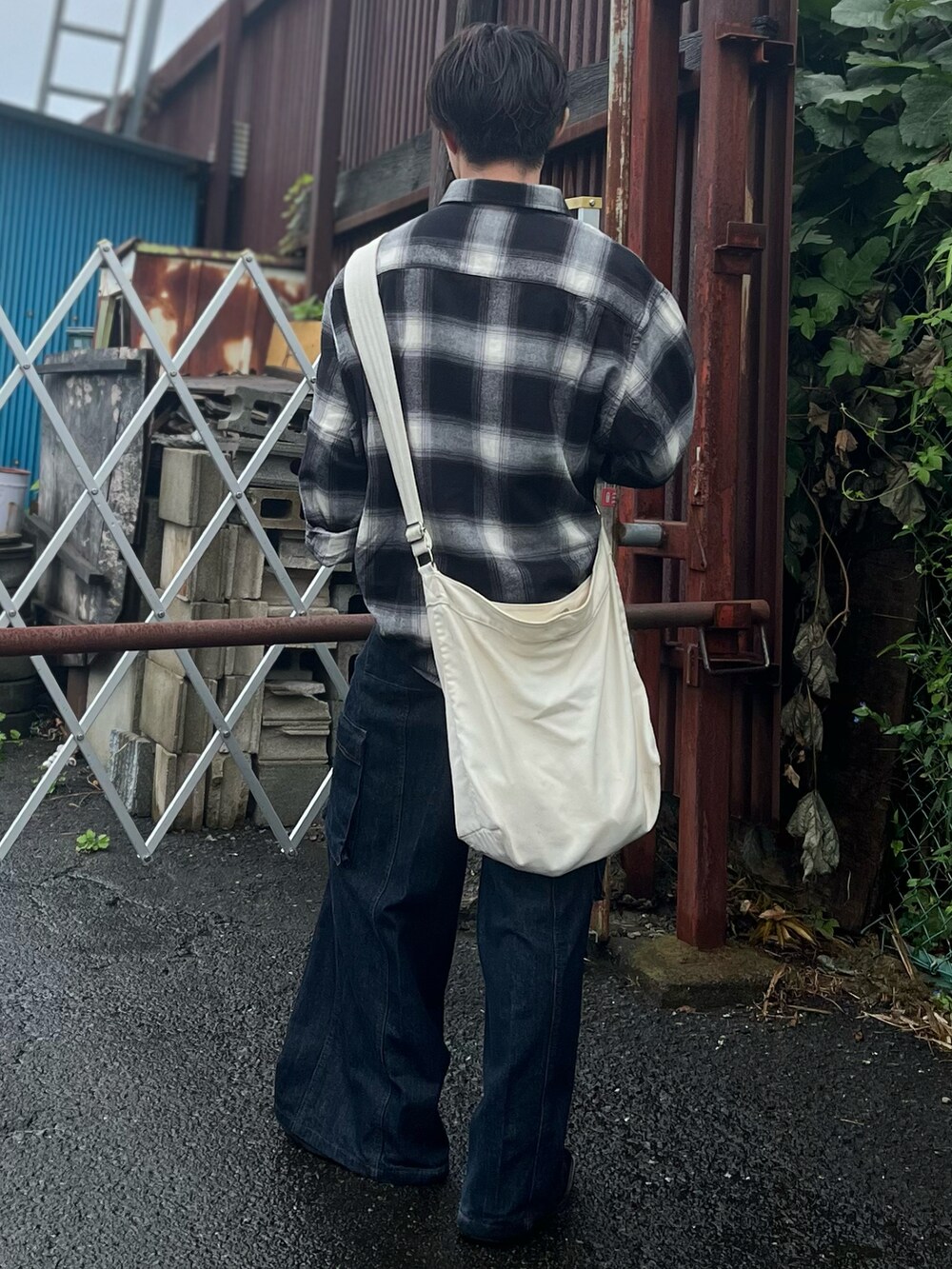 ブラック系のシャツ/ブラウス、ベージュ系のショルダーバッグ、ブルー系のデニムパンツを着用したメンズの秋コーディネートの5枚目の写真