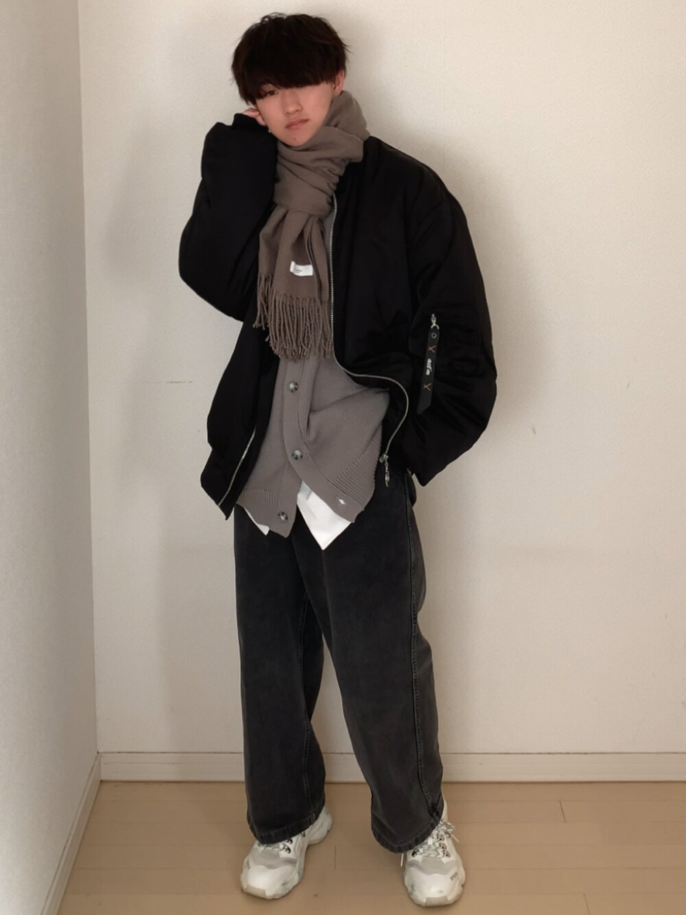 グレー系のデニムパンツ、ホワイト系のスニーカー、ブラック系のMA-1を着用したメンズの冬コーディネートの3枚目の写真