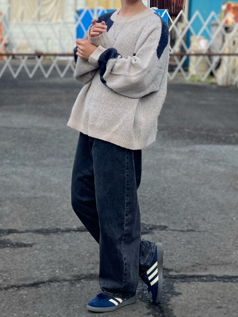 グレー系のデニムパンツ、ブルー系のニット/セーター、ブルー系のスニーカーを着用したメンズの秋コーディネートの4枚目の写真