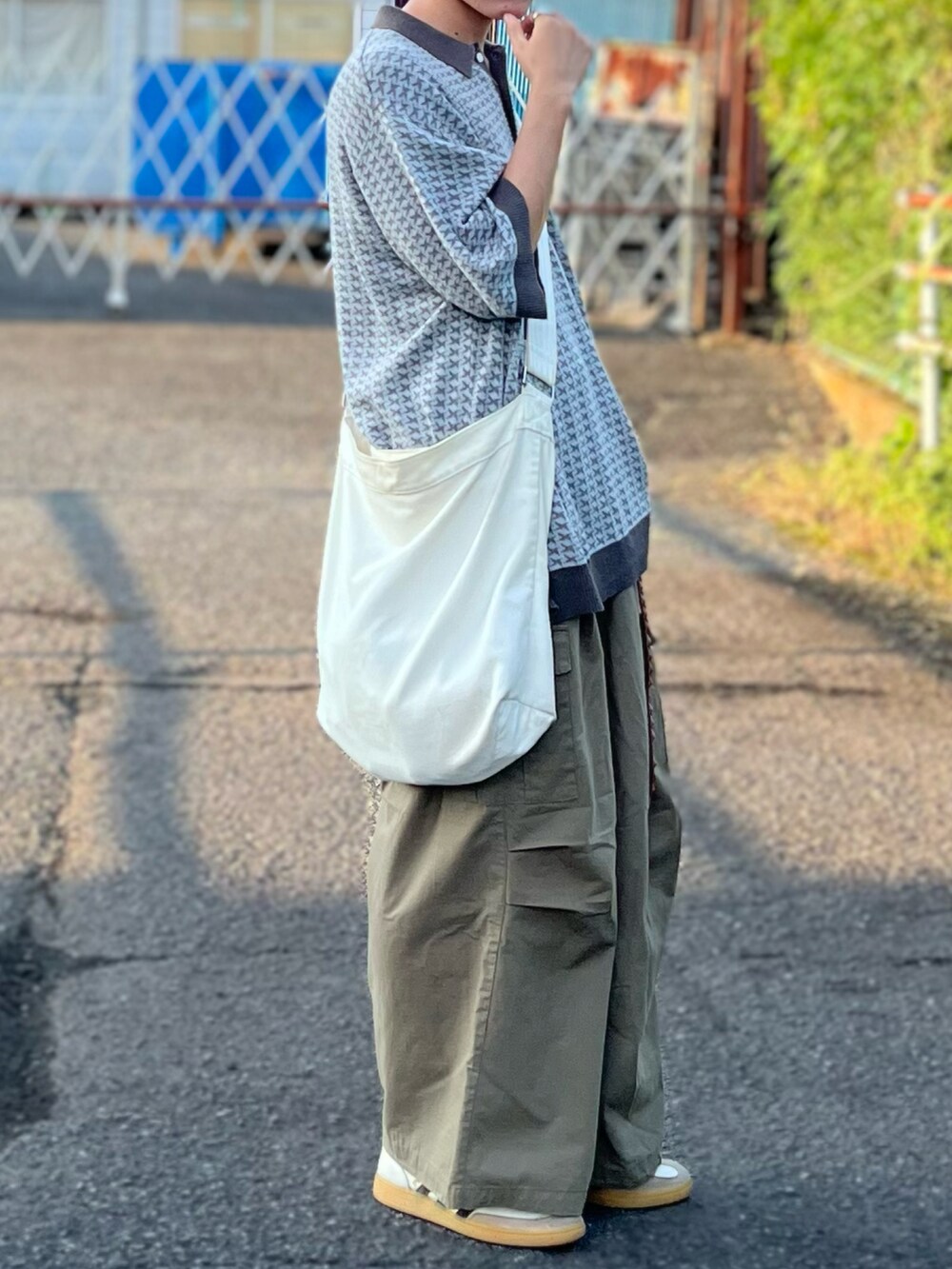 ベージュ系のショルダーバッグ、グリーン系のポロシャツ、グリーン系のカーゴパンツを着用したメンズの夏コーディネートの5枚目の写真