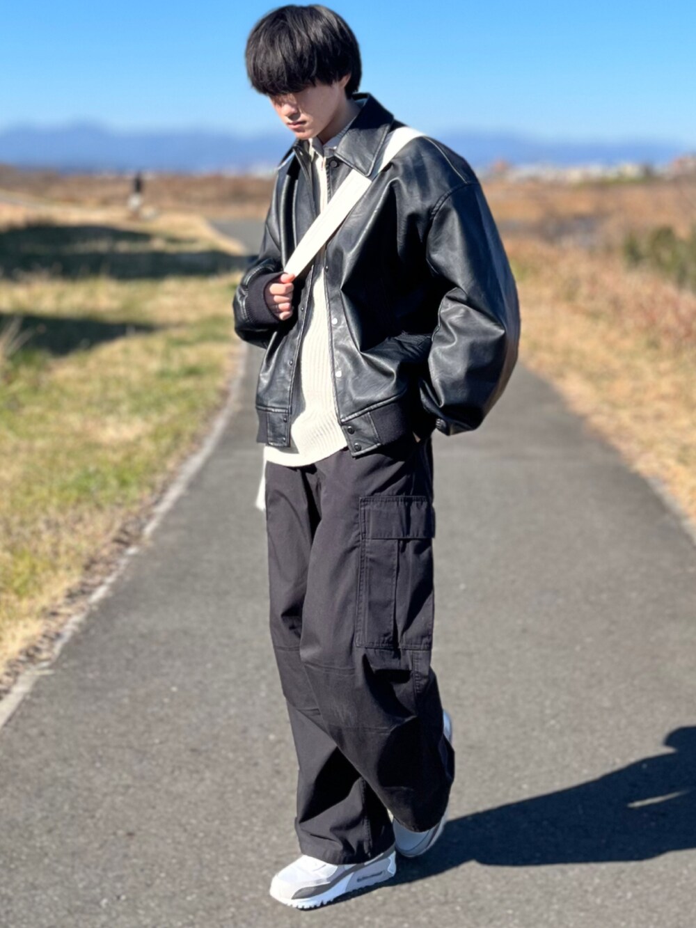 ブラック系のカーゴパンツ、ブラック系のブルゾン、ホワイト系のニット/セーターを着用したメンズの冬コーディネートの3枚目の写真