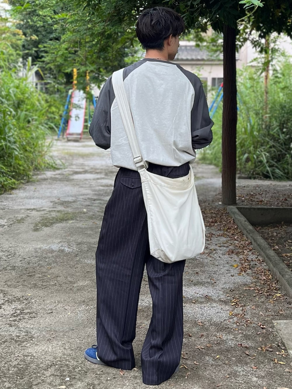 グレー系のスラックス、グレー系のTシャツ/カットソー、ブルー系のスニーカーを着用したメンズの秋コーディネートの5枚目の写真