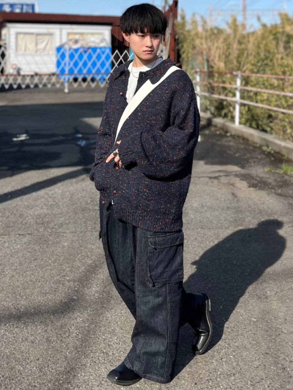 ブルー系のデニムパンツ、ブルー系のニット/セーター、ベージュ系のショルダーバッグを着用したメンズの冬コーディネートの3枚目の写真