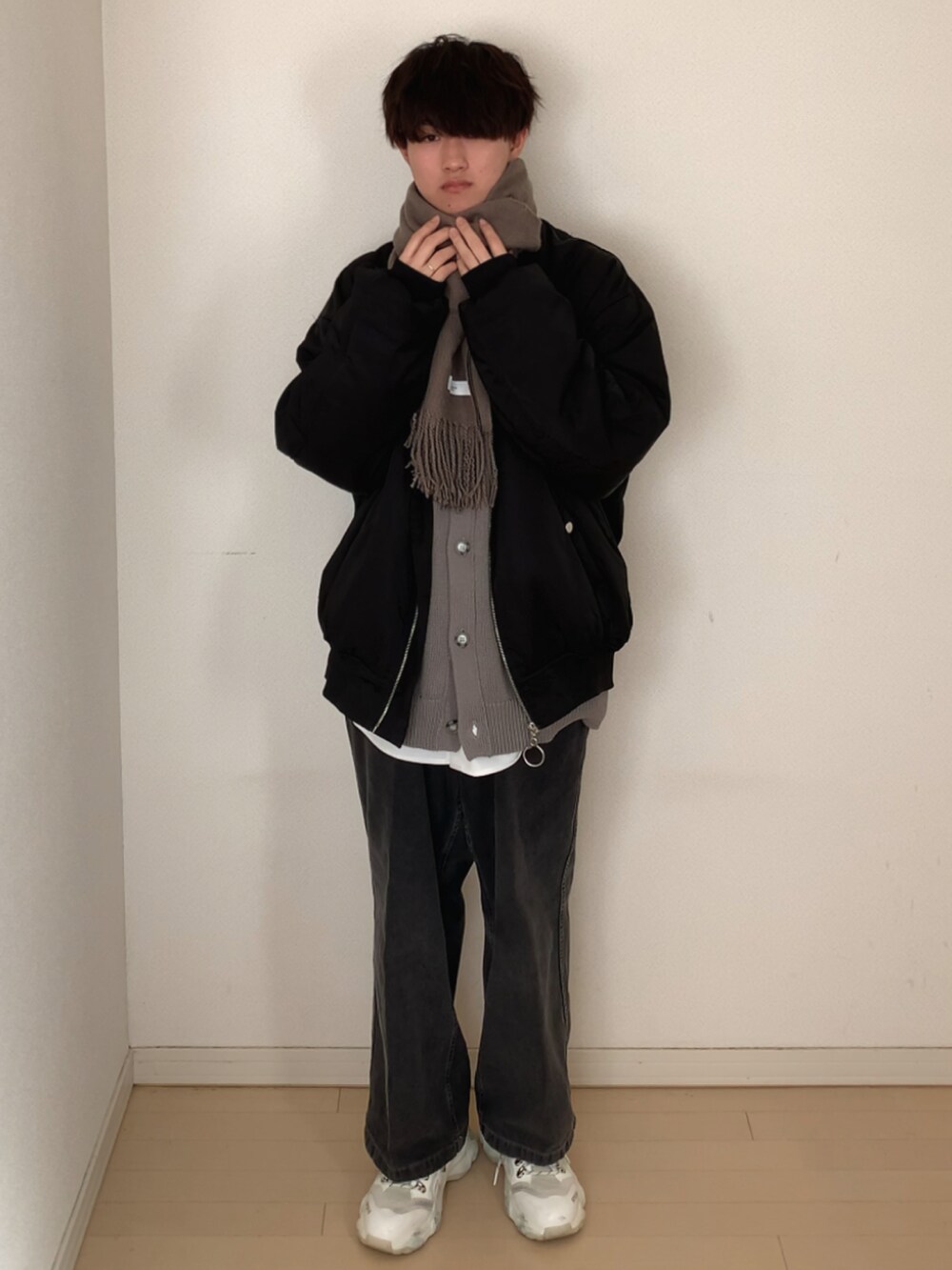 グレー系のデニムパンツ、ホワイト系のスニーカー、ブラック系のMA-1を着用したメンズの冬コーディネートの4枚目の写真