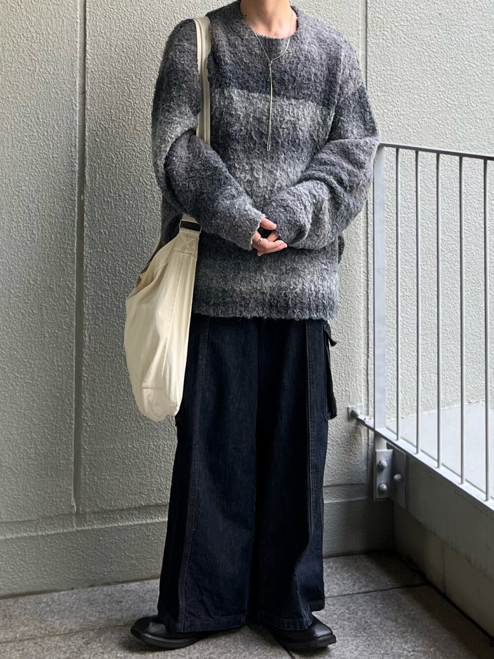 ベージュ系のショルダーバッグ、ブルー系のデニムパンツ、ブラック系のニット/セーターを着用したメンズの秋コーディネートの2枚目の写真