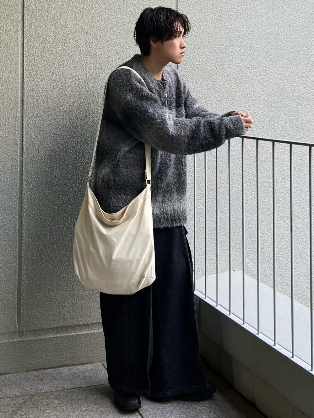 ベージュ系のショルダーバッグ、ブルー系のデニムパンツ、ブラック系のニット/セーターを着用したメンズの秋コーディネートの3枚目の写真