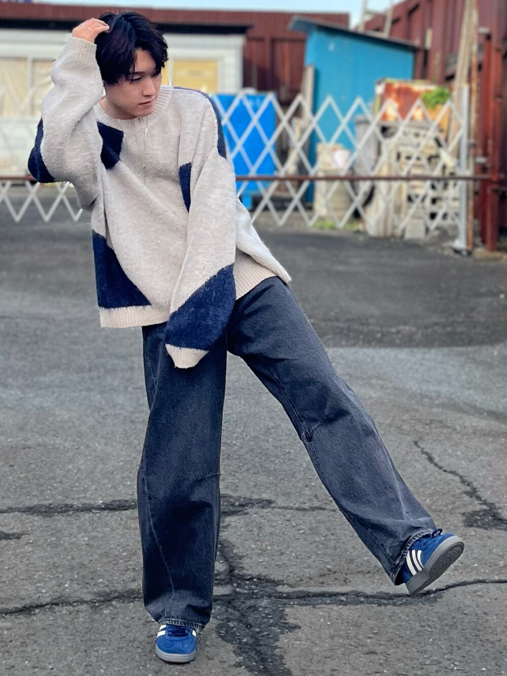 グレー系のデニムパンツ、ブルー系のニット/セーター、ブルー系のスニーカーを着用したメンズの秋コーディネートの3枚目の写真