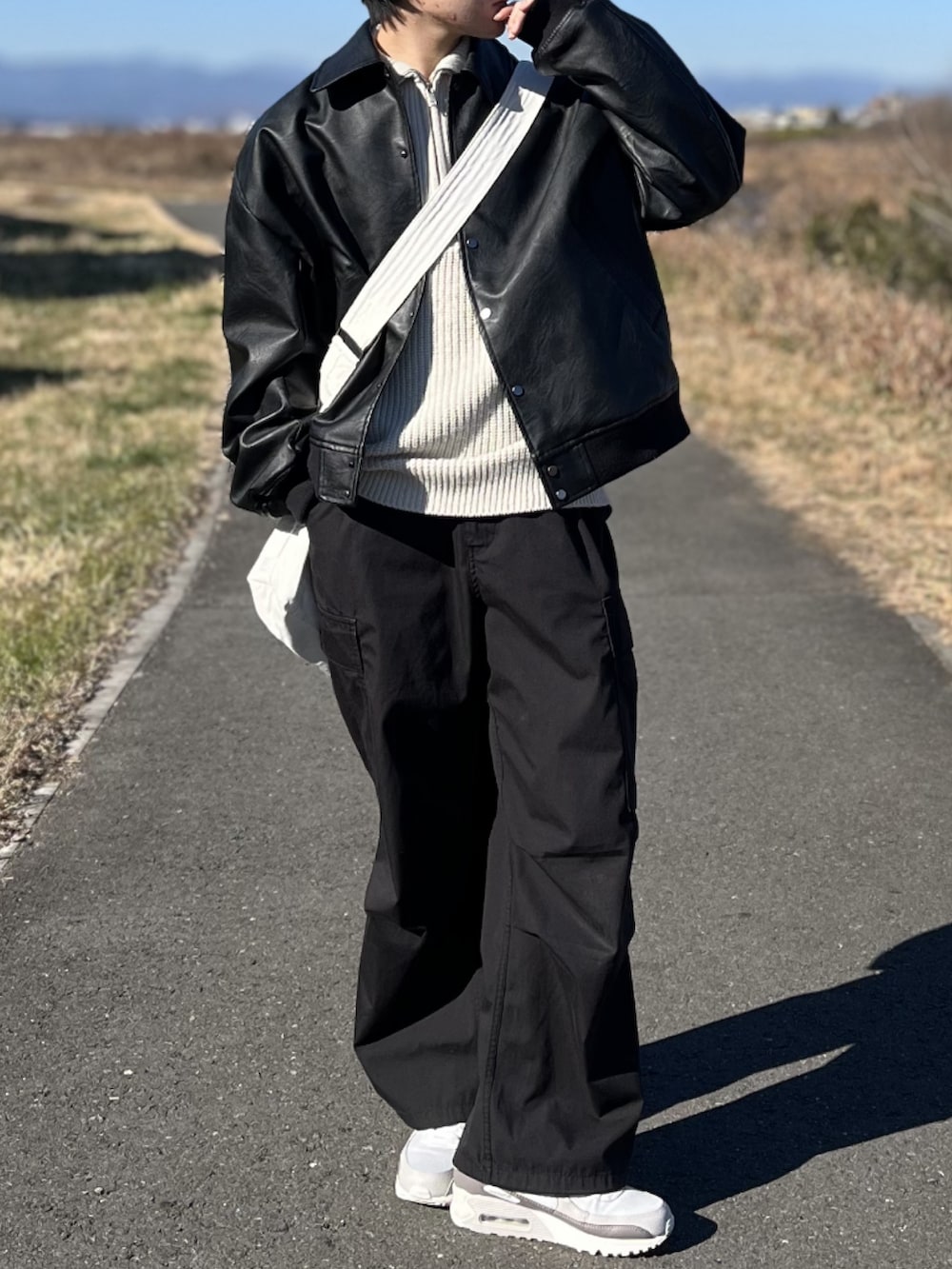 ブラック系のカーゴパンツ、ブラック系のブルゾン、ホワイト系のニット/セーターを着用したメンズの冬コーディネートの2枚目の写真