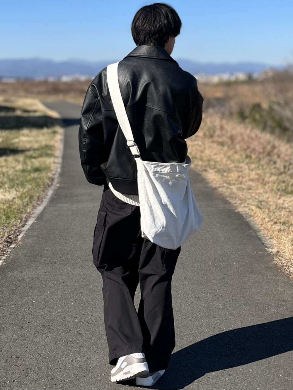 ブラック系のカーゴパンツ、ブラック系のブルゾン、ホワイト系のニット/セーターを着用したメンズの冬コーディネートの5枚目の写真