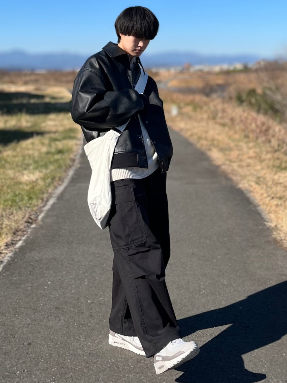 ブラック系のカーゴパンツ、ブラック系のブルゾン、ホワイト系のニット/セーターを着用したメンズの冬コーディネートの4枚目の写真