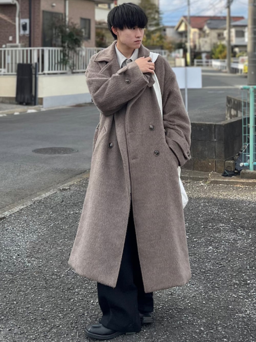 ブラック系のスラックス、ブラック系のブーツ、ブラウン系のチェスターコートを着用したメンズの冬コーディネートの3枚目の写真