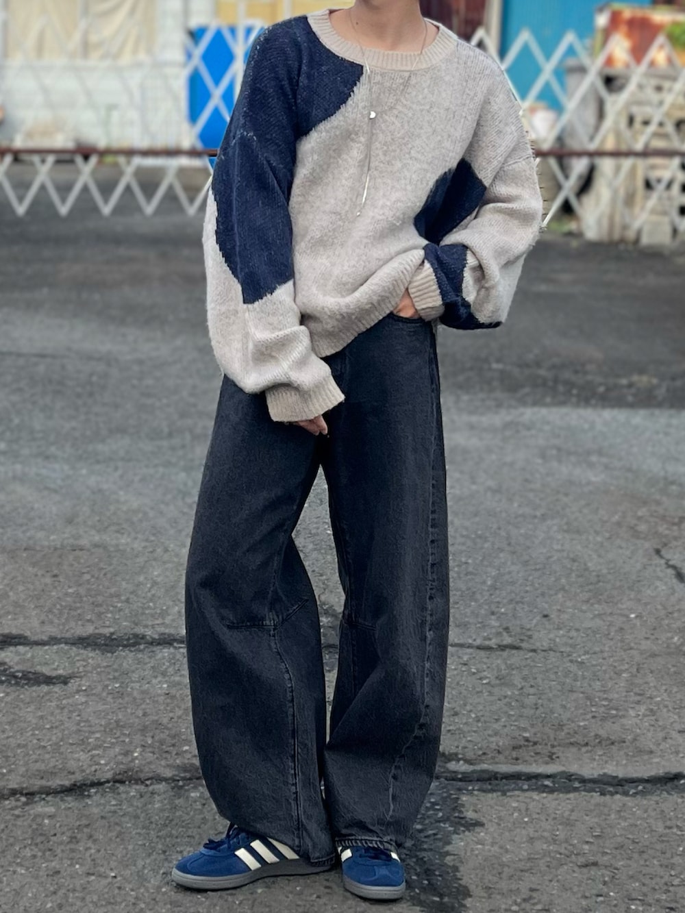 グレー系のデニムパンツ、ブルー系のニット/セーター、ブルー系のスニーカーを着用したメンズの秋コーディネートの2枚目の写真