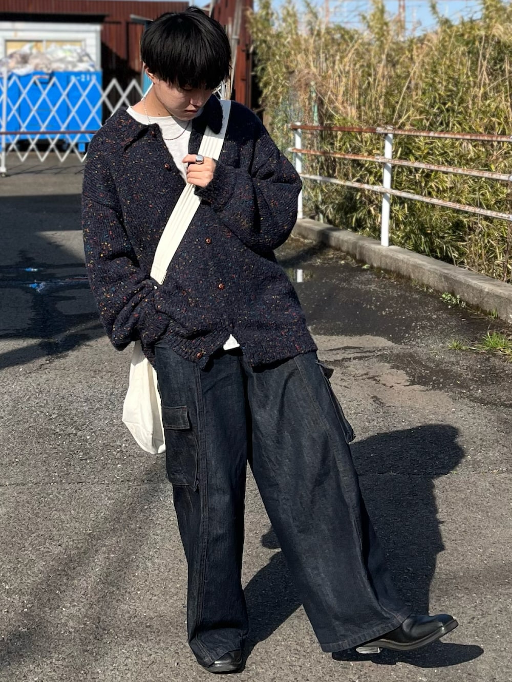 ブルー系のデニムパンツ、ブルー系のニット/セーター、ベージュ系のショルダーバッグを着用したメンズの冬コーディネートの4枚目の写真