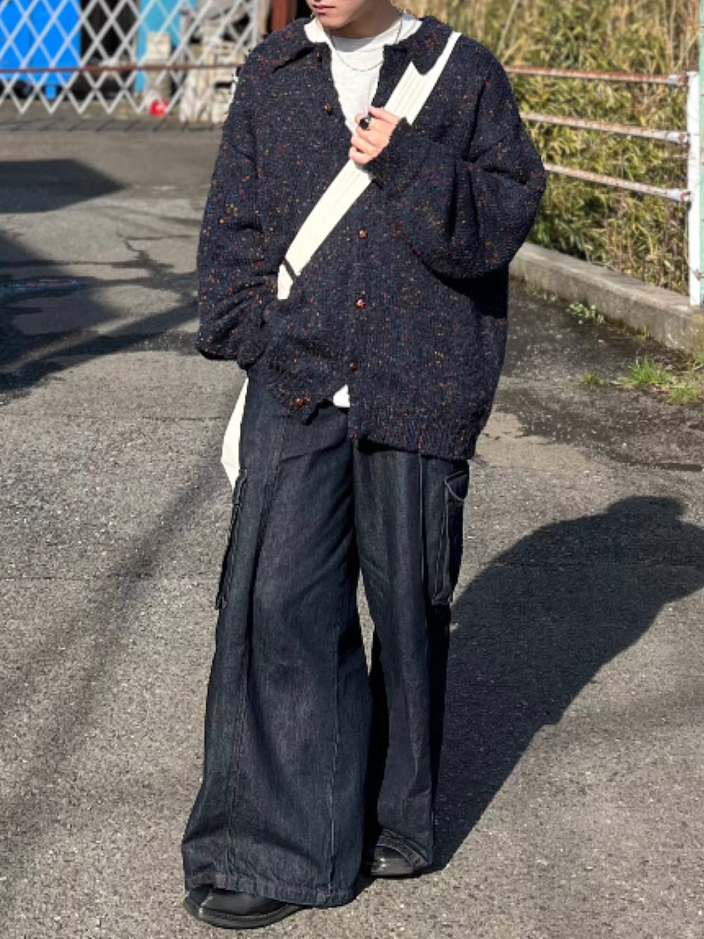 ブルー系のデニムパンツ、ブルー系のニット/セーター、ベージュ系のショルダーバッグを着用したメンズの冬コーディネートの2枚目の写真