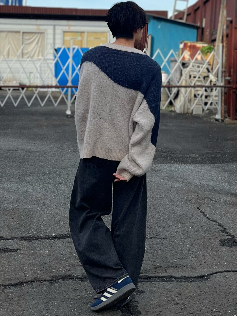 グレー系のデニムパンツ、ブルー系のニット/セーター、ブルー系のスニーカーを着用したメンズの秋コーディネートの5枚目の写真