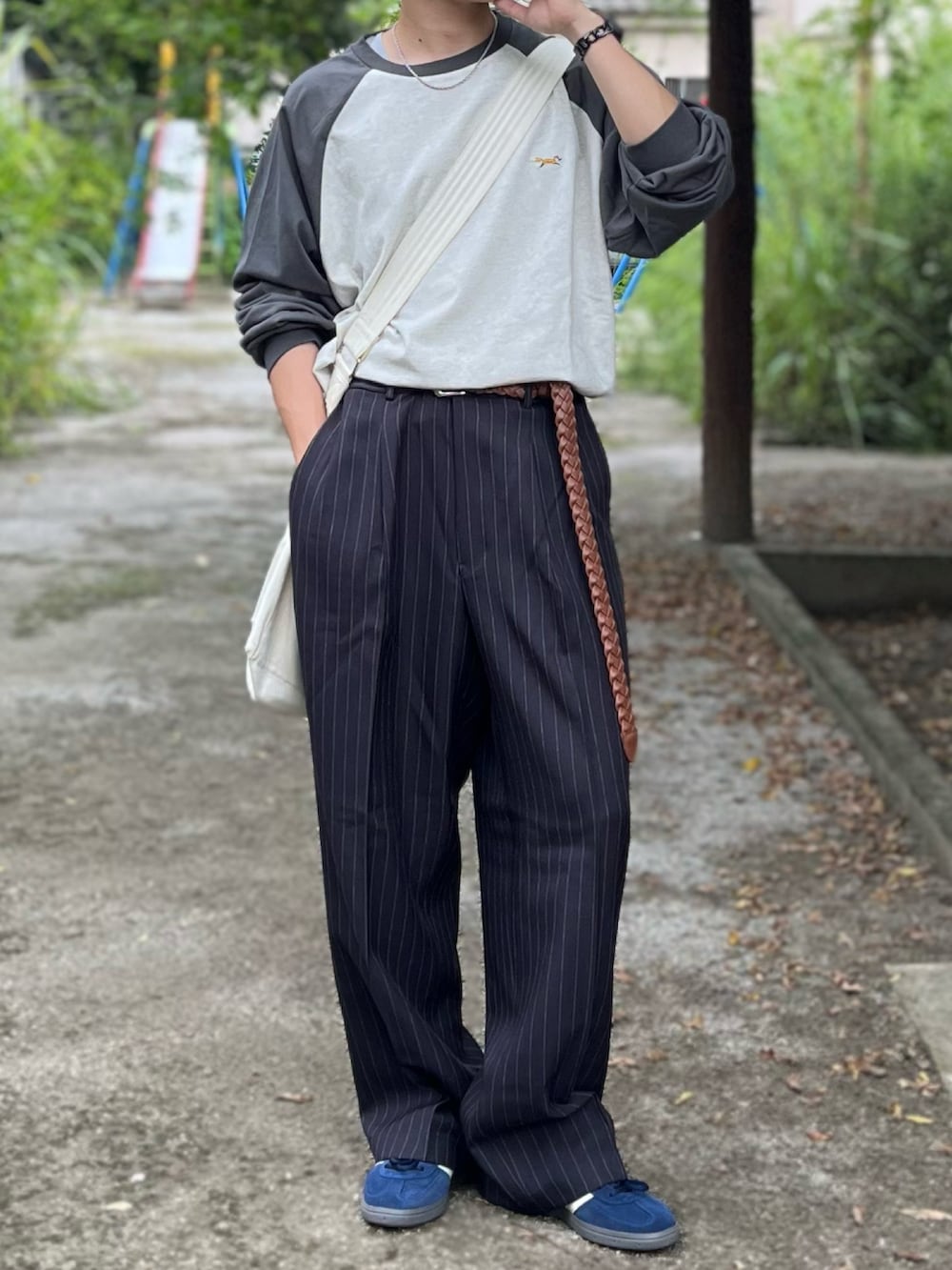 グレー系のスラックス、グレー系のTシャツ/カットソー、ブルー系のスニーカーを着用したメンズの秋コーディネートの2枚目の写真