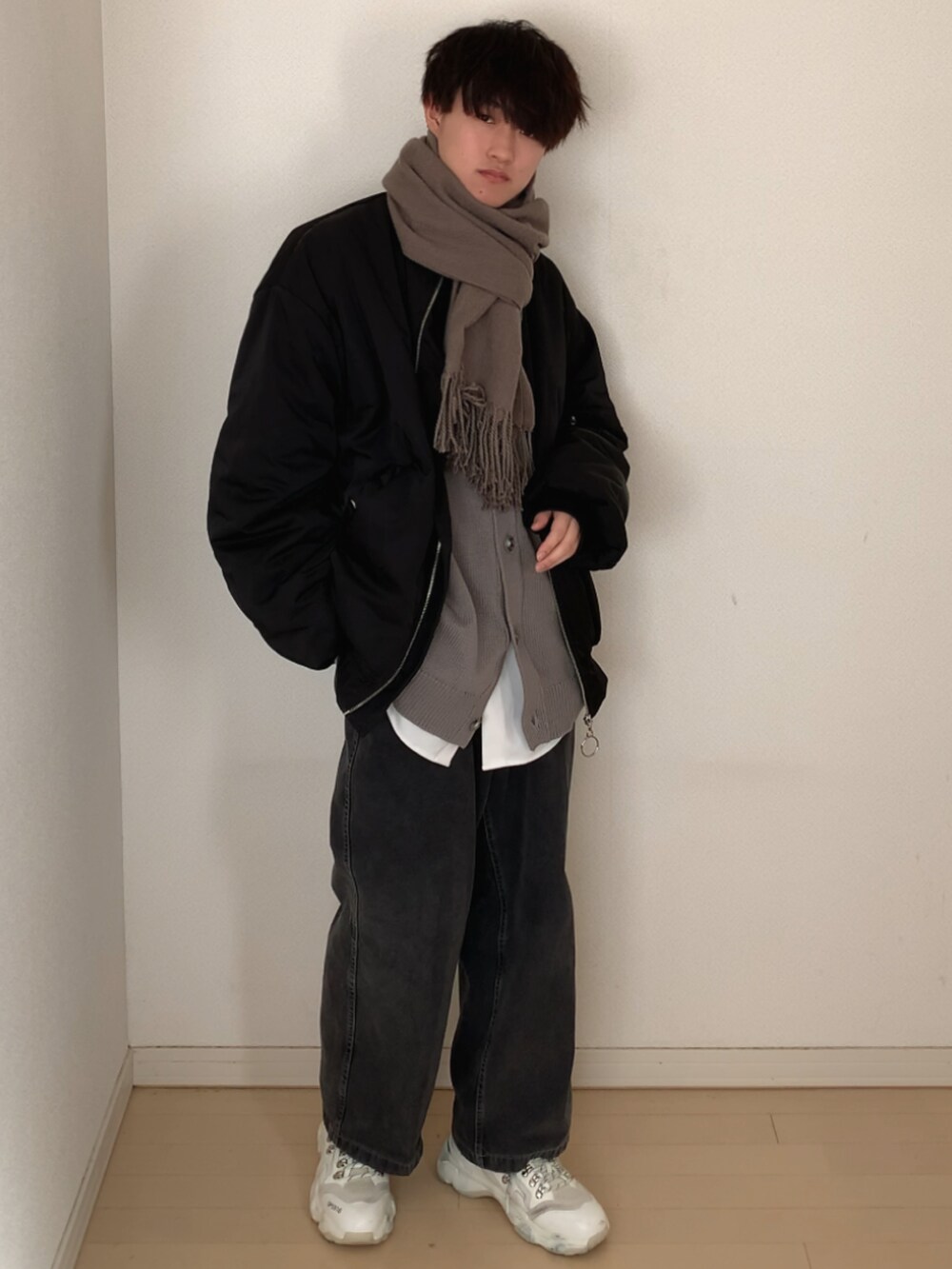 グレー系のデニムパンツ、ホワイト系のスニーカー、ブラック系のMA-1を着用したメンズの冬コーディネートの2枚目の写真