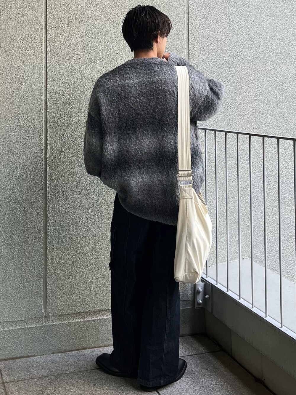 ベージュ系のショルダーバッグ、ブルー系のデニムパンツ、ブラック系のニット/セーターを着用したメンズの秋コーディネートの5枚目の写真