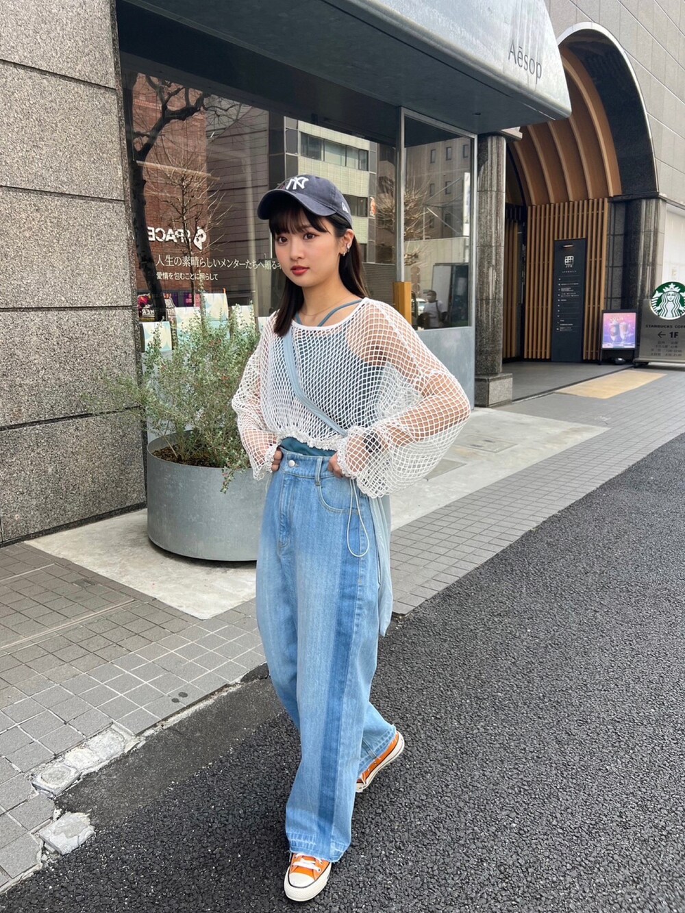 ブルー系のデニムパンツ、グリーン系のショルダーバッグ、ホワイト系のTシャツ/カットソーを着用したレディースの春コーディネートの2枚目の写真