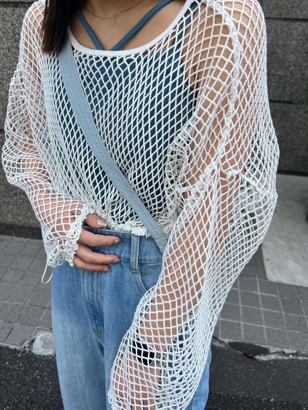 ブルー系のデニムパンツ、グリーン系のショルダーバッグ、ホワイト系のTシャツ/カットソーを着用したレディースの春コーディネートの4枚目の写真