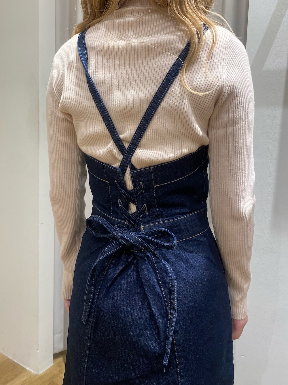 ホワイト系のニット/セーター、ブルー系のジャンパースカート、ブラック系のブーツを着用したレディースの冬コーディネートの3枚目の写真