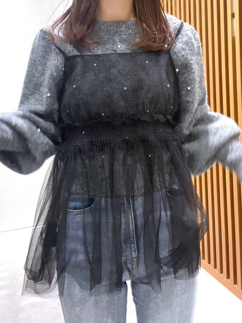 グレー系のニット/セーター、ブラック系のシャツ/ブラウス、ブルー系のデニムパンツを着用したレディースの冬コーディネートの4枚目の写真