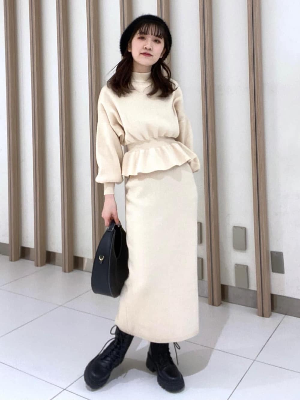 ホワイト系のワンピース、ブラック系のブーツ、ブラック系のショルダーバッグを着用したレディースの冬コーディネートの3枚目の写真