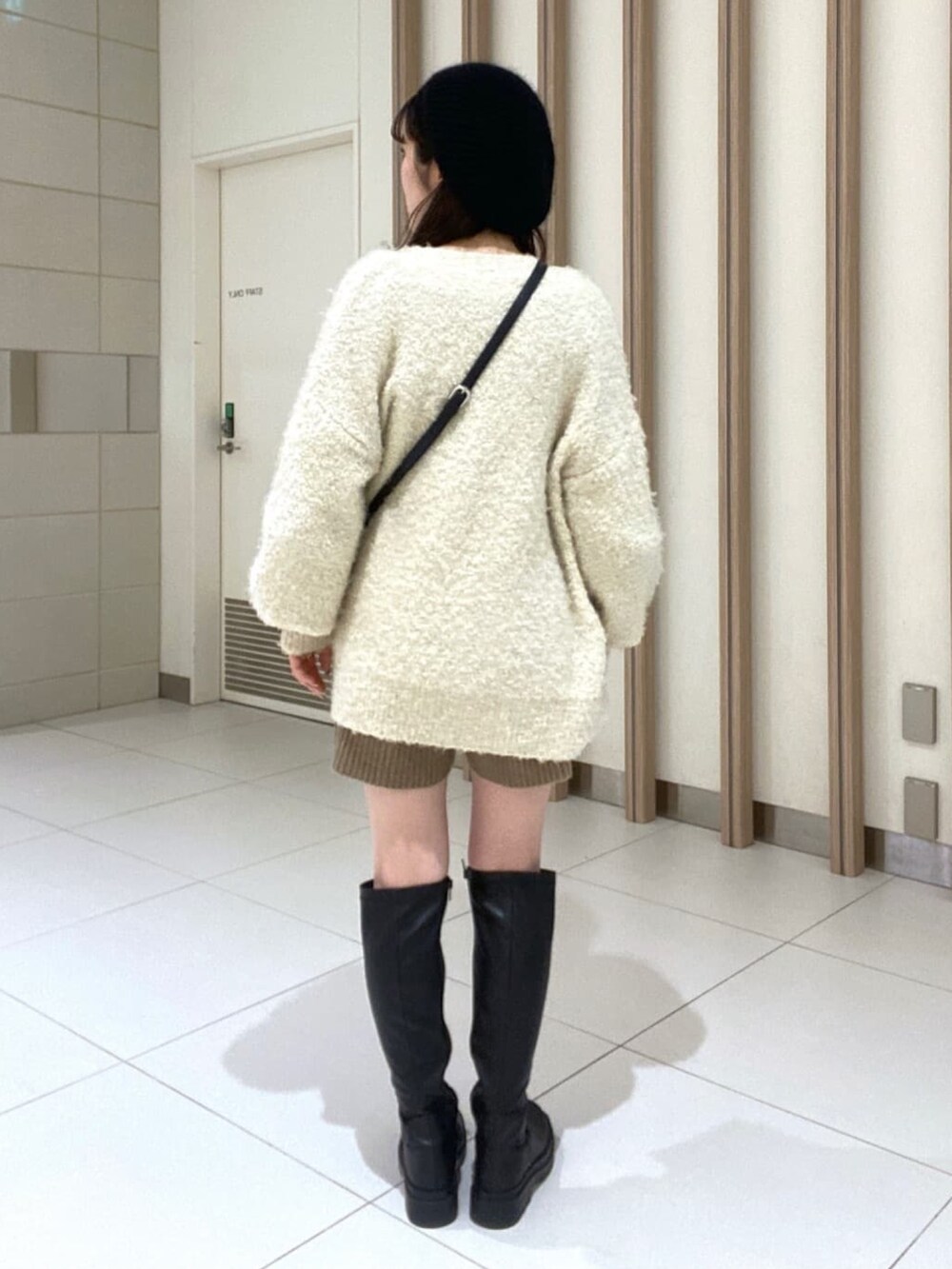 ホワイト系のカーディガン/ボレロ、ブラウン系のワンピース、ブラック系のブーツを着用したレディースの冬コーディネートの3枚目の写真