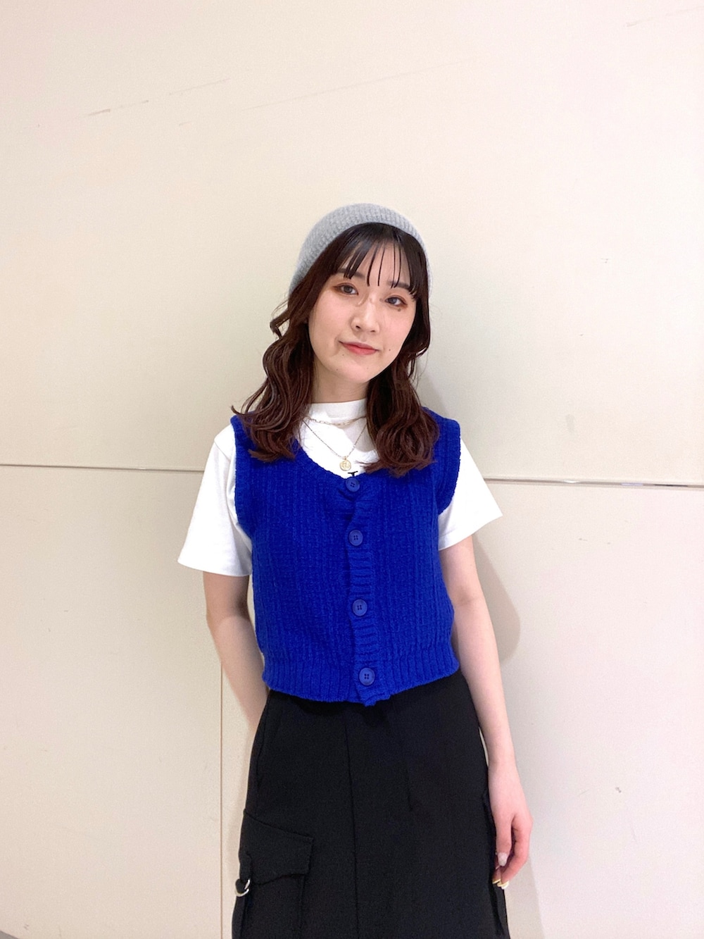 ブルー系のベスト、ホワイト系のTシャツ/カットソー、ブラック系のスカートを着用したレディースの春コーディネートの5枚目の写真