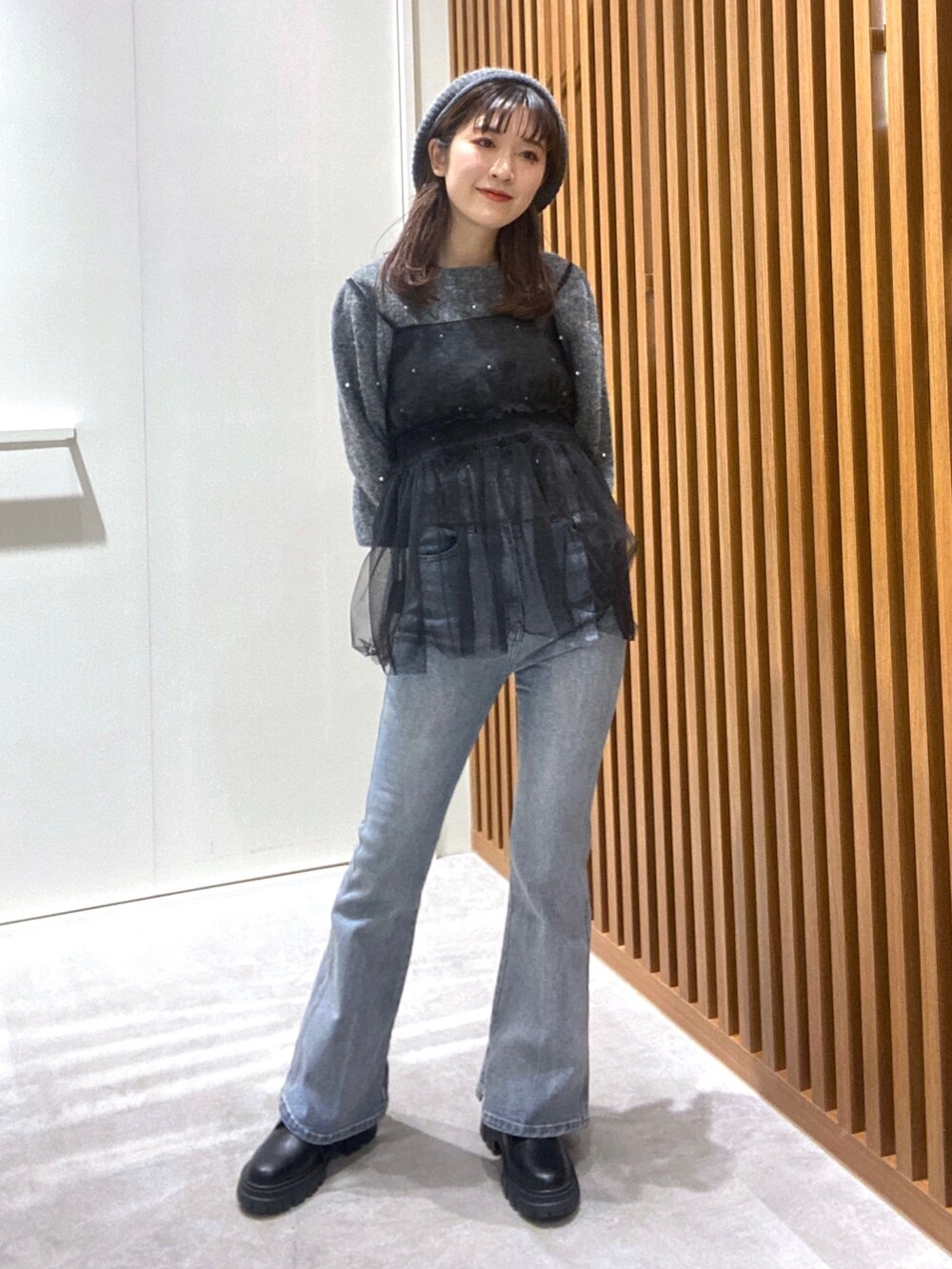 グレー系のニット/セーター、ブラック系のシャツ/ブラウス、ブルー系のデニムパンツを着用したレディースの冬コーディネートの2枚目の写真