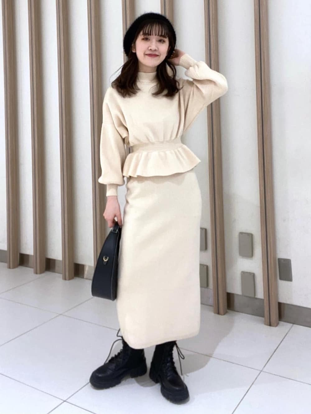 ホワイト系のワンピース、ブラック系のブーツ、ブラック系のショルダーバッグを着用したレディースの冬コーディネートの2枚目の写真