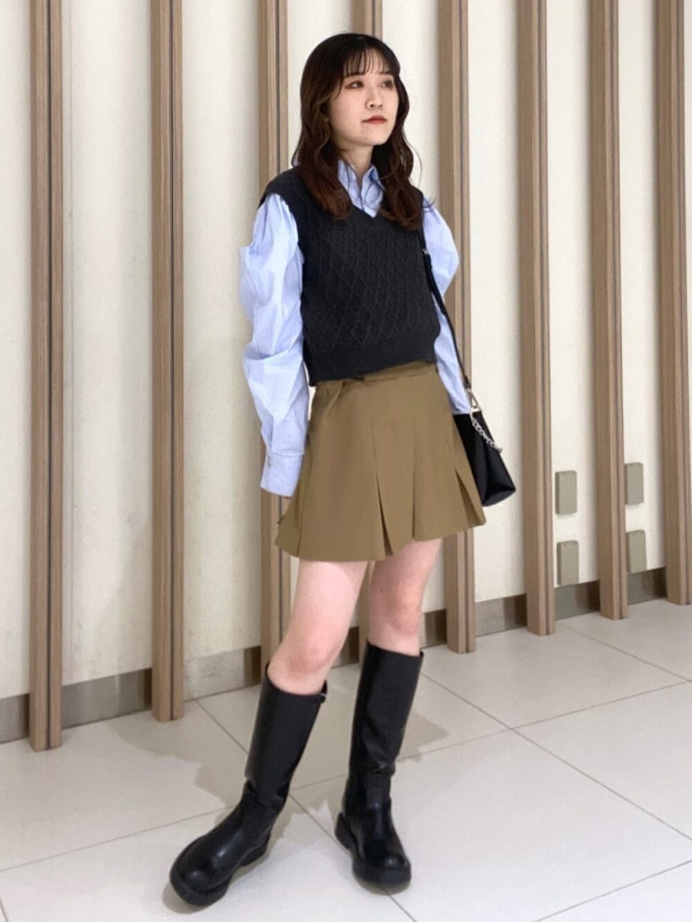 ブルー系のシャツ/ブラウス、ベージュ系のスカート、ブラック系のブーツを着用したレディースの冬コーディネートの2枚目の写真