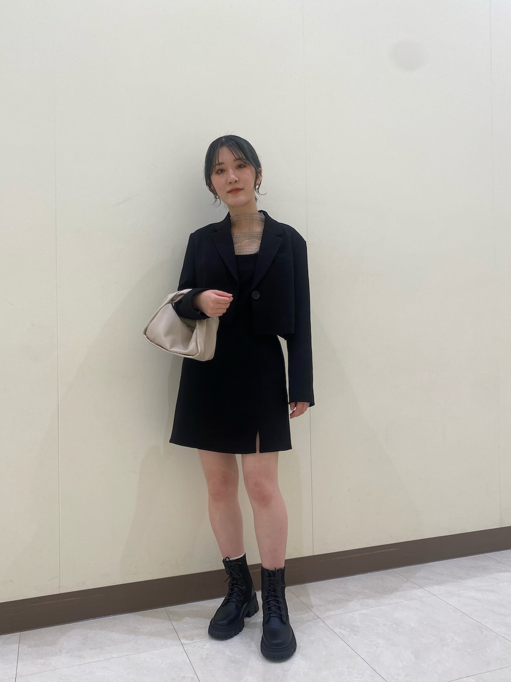 ブラック系のテーラードジャケット、ブラック系のワンピース、ベージュ系のTシャツ/カットソーを着用したレディースの秋コーディネートの2枚目の写真