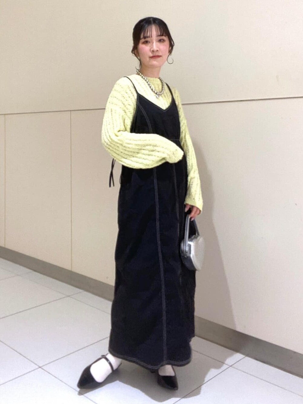 イエロー系のニット/セーター、ブラック系のワンピース、ブラック系のパンプスを着用したレディースの春コーディネートの3枚目の写真