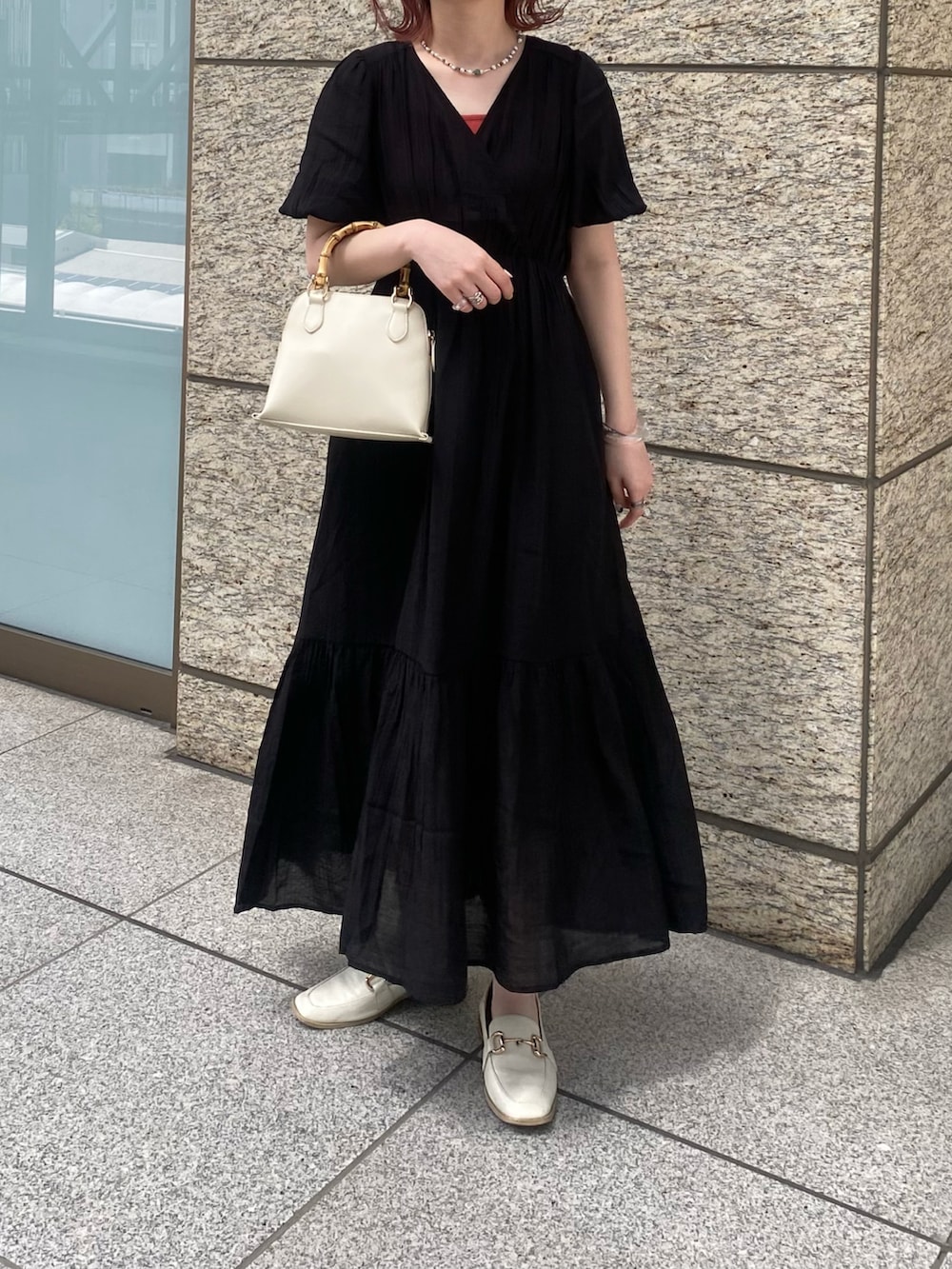 ブラック系のワンピース、ホワイト系のショルダーバッグ、レッド系のニット/セーターを着用したレディースの春コーディネートの3枚目の写真