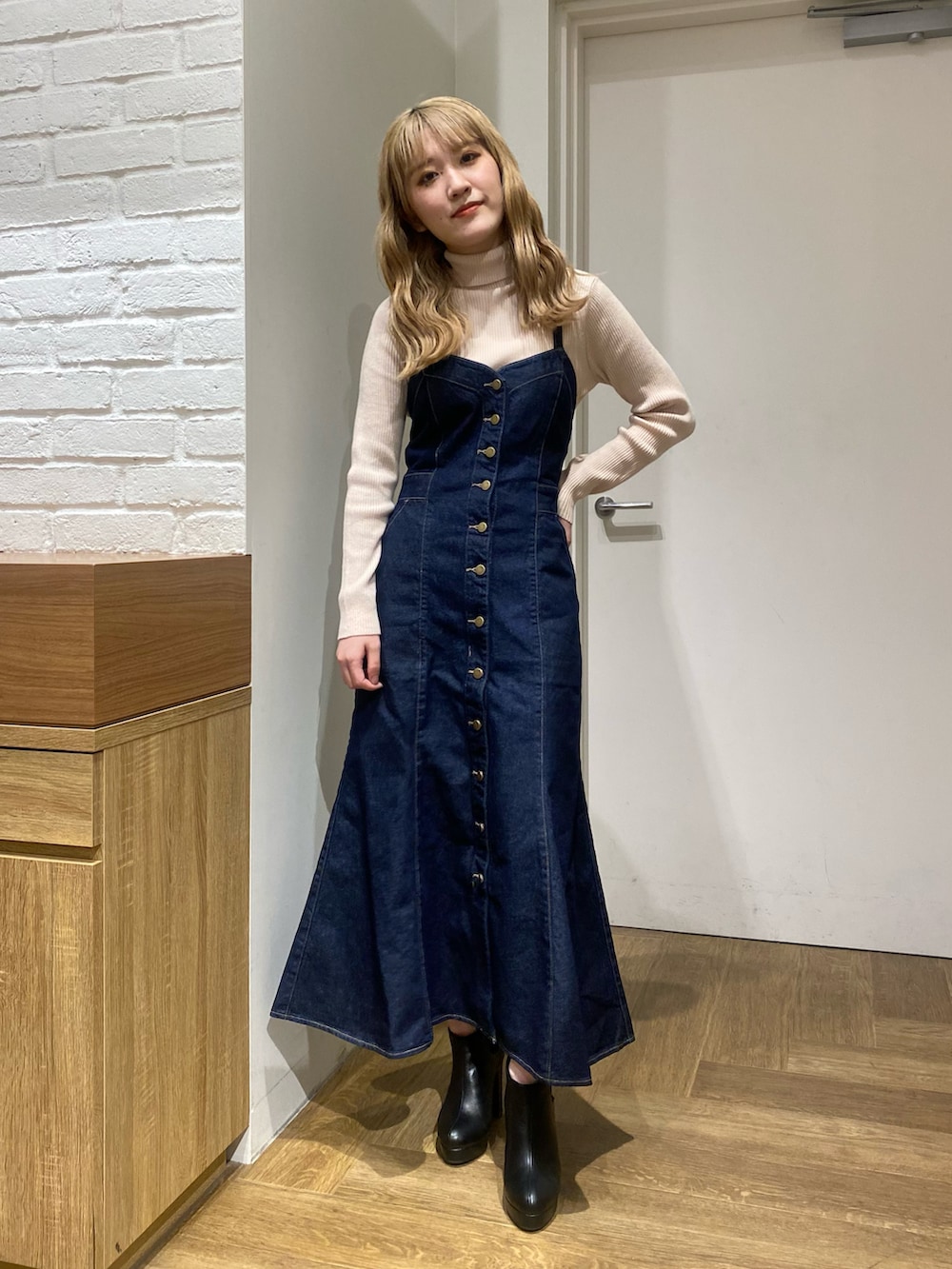 ホワイト系のニット/セーター、ブルー系のジャンパースカート、ブラック系のブーツを着用したレディースの冬コーディネートの2枚目の写真