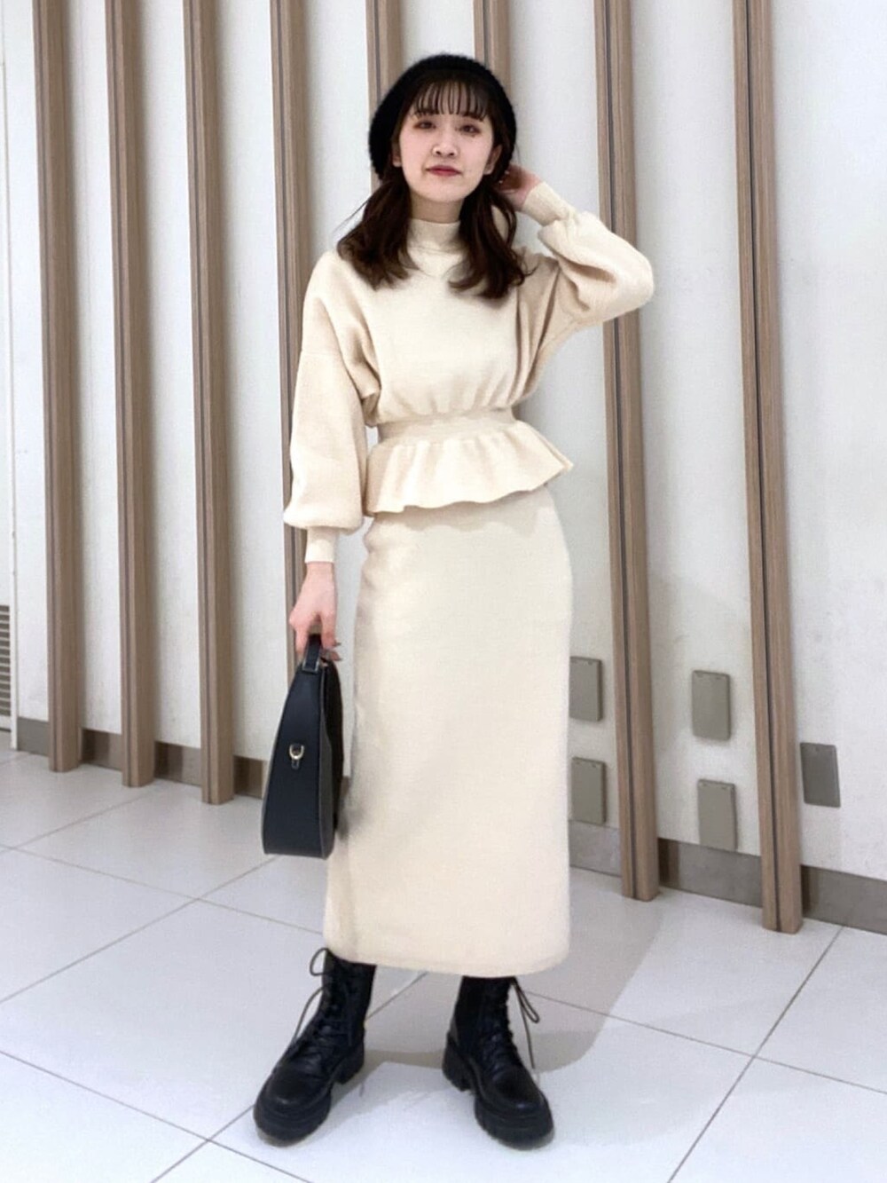 ホワイト系のワンピース、ブラック系のブーツ、ブラック系のショルダーバッグを着用したレディースの冬コーディネートの4枚目の写真