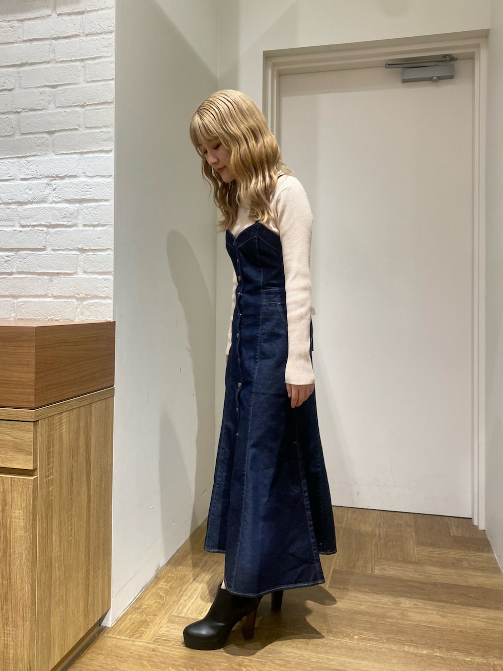 ホワイト系のニット/セーター、ブルー系のジャンパースカート、ブラック系のブーツを着用したレディースの冬コーディネートの4枚目の写真