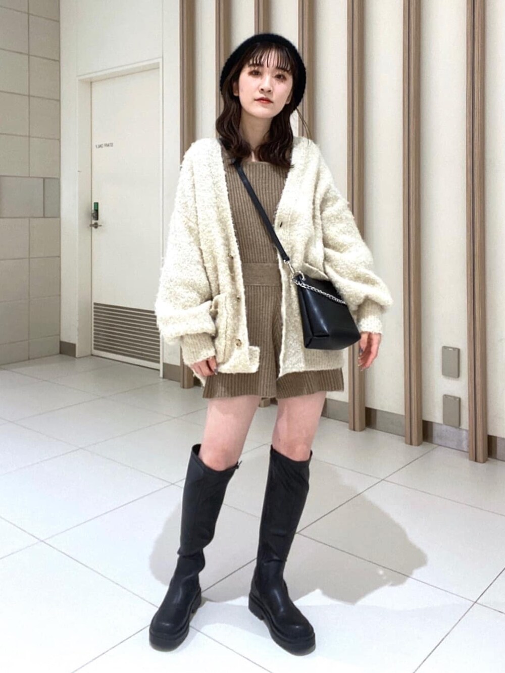 ホワイト系のカーディガン/ボレロ、ブラウン系のワンピース、ブラック系のブーツを着用したレディースの冬コーディネートの2枚目の写真