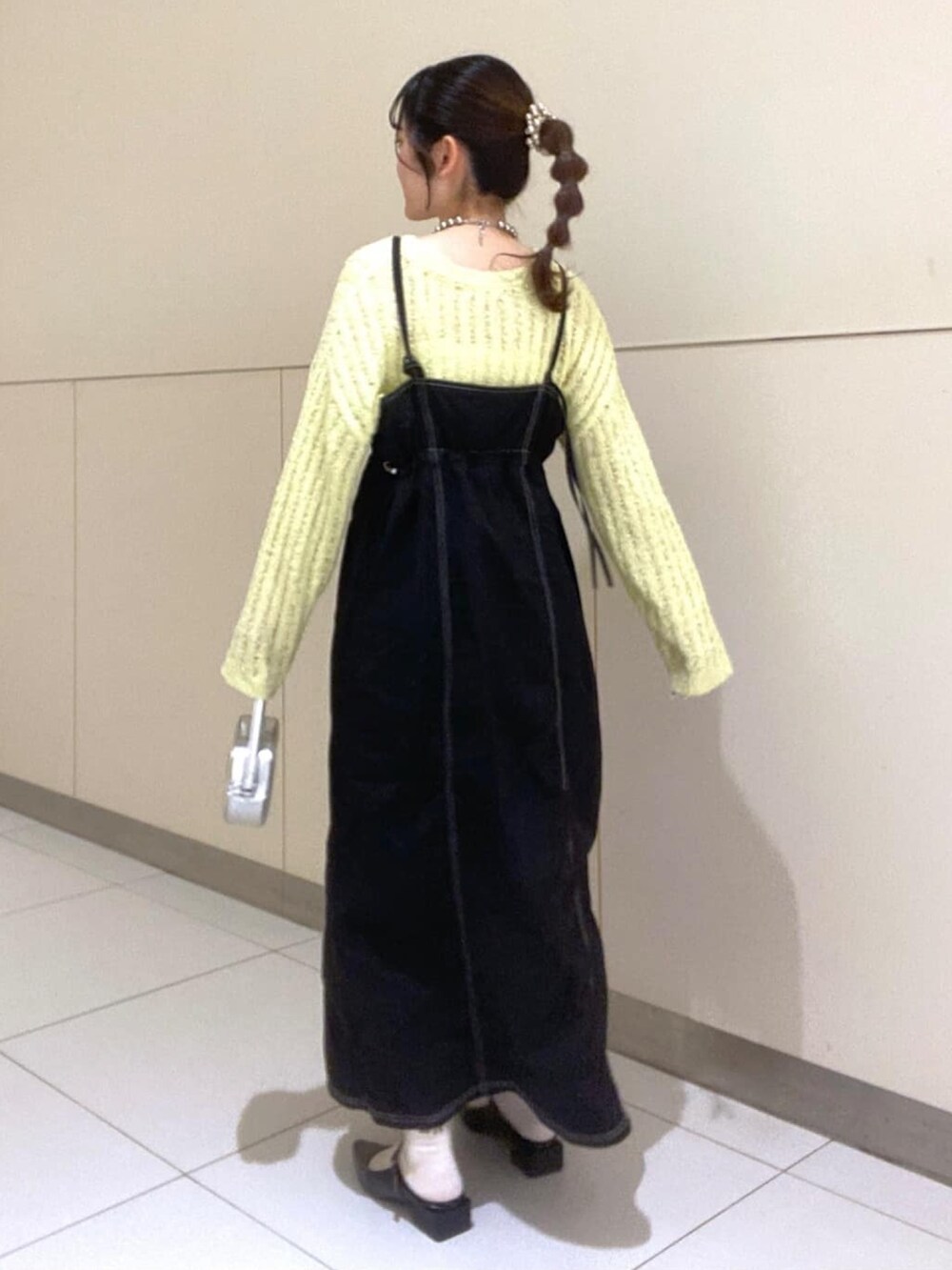 イエロー系のニット/セーター、ブラック系のワンピース、ブラック系のパンプスを着用したレディースの春コーディネートの2枚目の写真