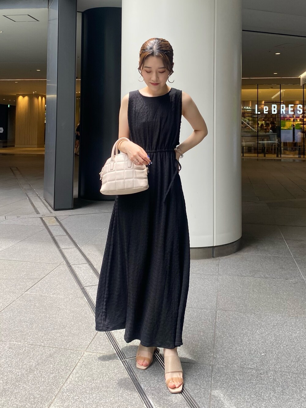 ブラック系のワンピース、グレー系のサンダル、ホワイト系のショルダーバッグを着用したレディースの夏コーディネートの2枚目の写真