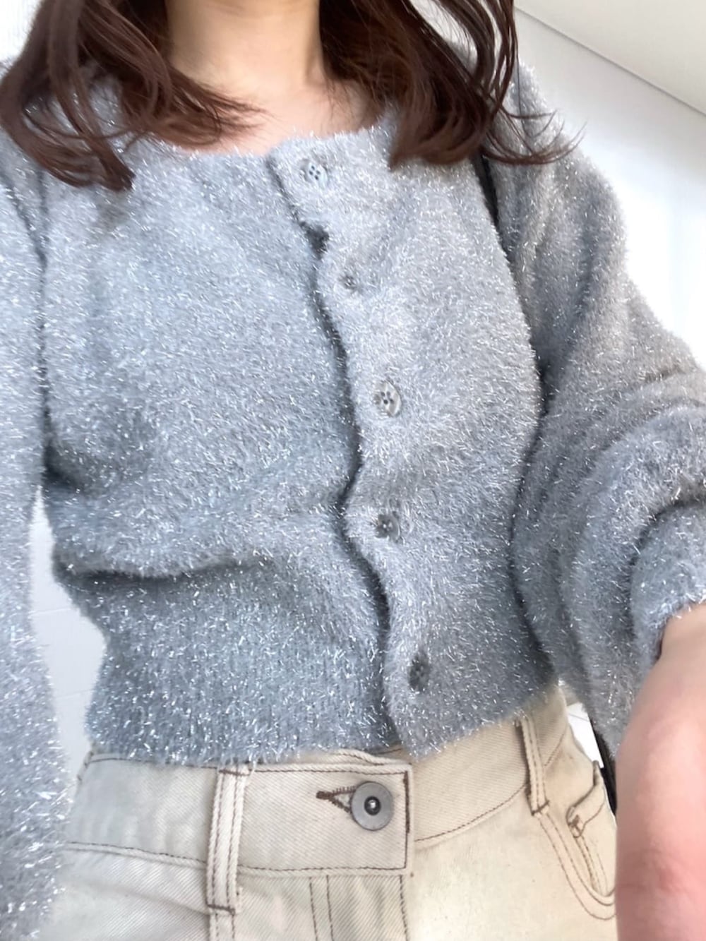 グレー系のニット/セーター、ホワイト系のデニムパンツ、ブラック系のショルダーバッグを着用したレディースの冬コーディネートの4枚目の写真