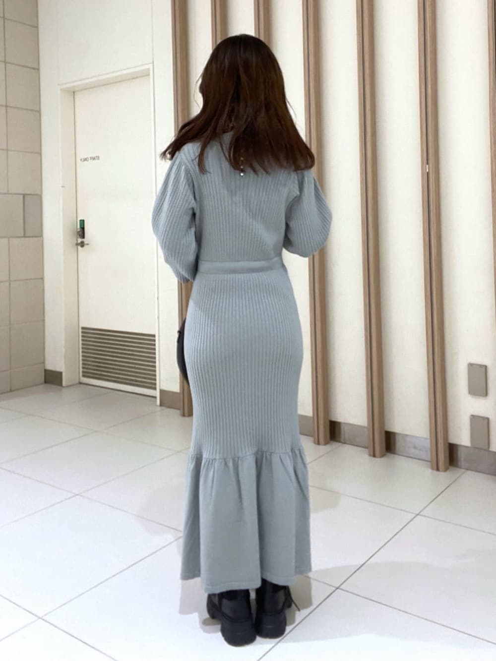 グリーン系のワンピース、ブラック系のブーツ、ブラック系のマフラーを着用したレディースの冬コーディネートの3枚目の写真