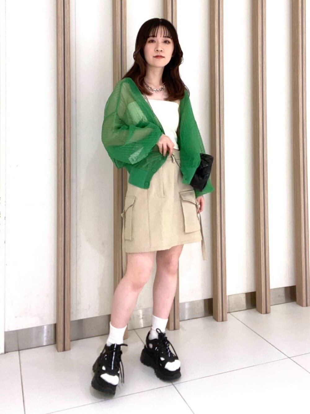 グリーン系のカーディガン/ボレロ、ホワイト系のキャミソール、ベージュ系のスカートを着用したレディースの春コーディネートの4枚目の写真