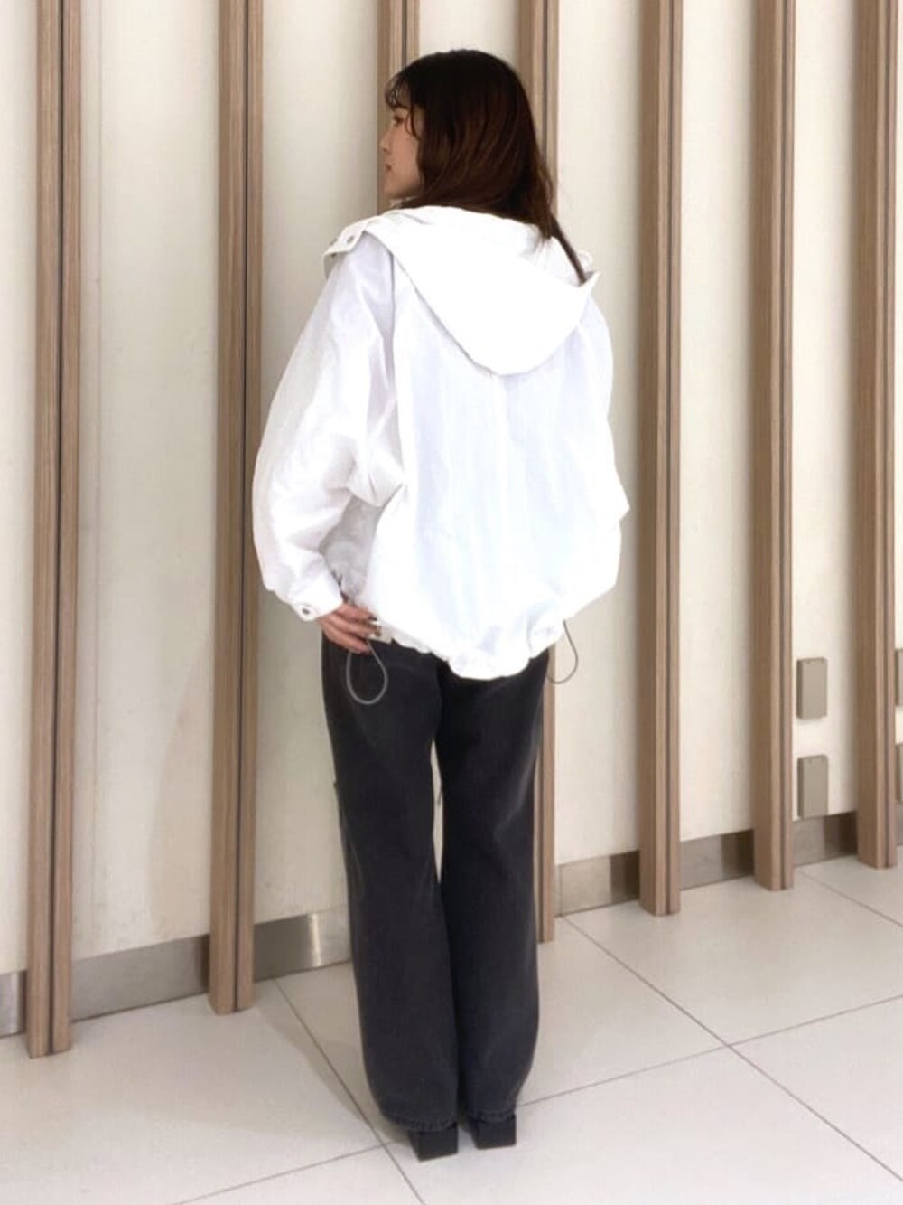 ホワイト系のマウンテンパーカー、レッド系のニット/セーター、ブラック系のパンプスを着用したレディースの春コーディネートの2枚目の写真