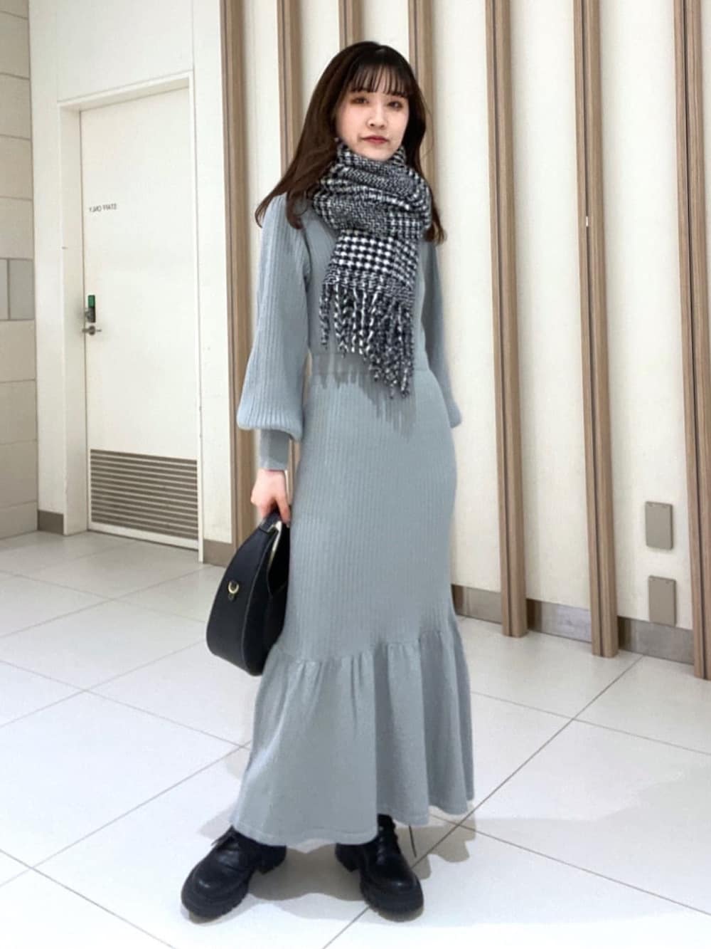 グリーン系のワンピース、ブラック系のブーツ、ブラック系のマフラーを着用したレディースの冬コーディネートの4枚目の写真