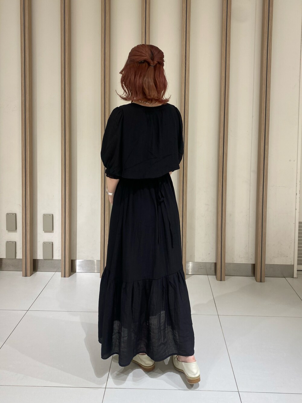 ブラック系のワンピース、ホワイト系のショルダーバッグ、レッド系のニット/セーターを着用したレディースの春コーディネートの2枚目の写真