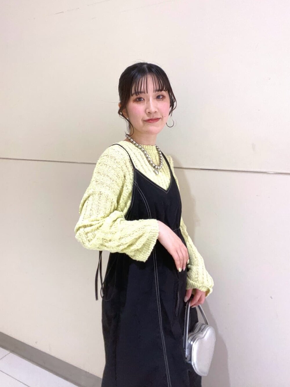 イエロー系のニット/セーター、ブラック系のワンピース、ブラック系のパンプスを着用したレディースの春コーディネートの4枚目の写真